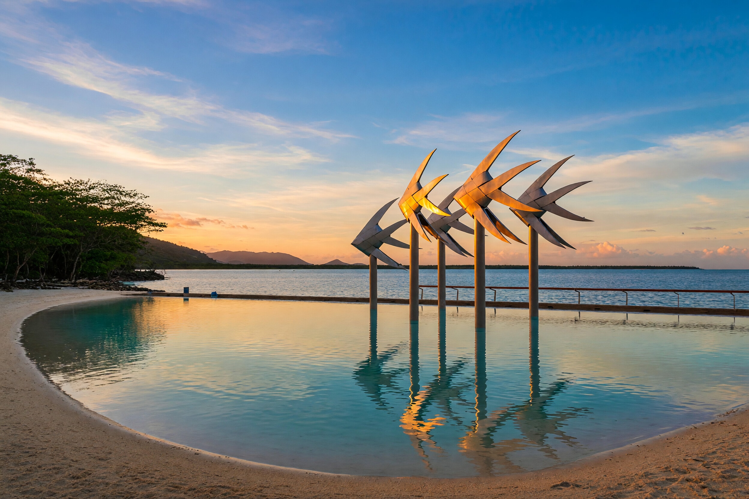 Esplanade Lagoon fish sculptures and Trinity Bay, Cairns, at sunset